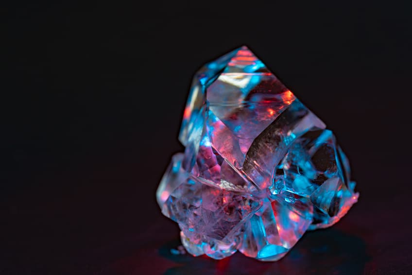 Diamante en bruto que se ilumina con múltiples colores bajo la luz | Litoterapia en línea